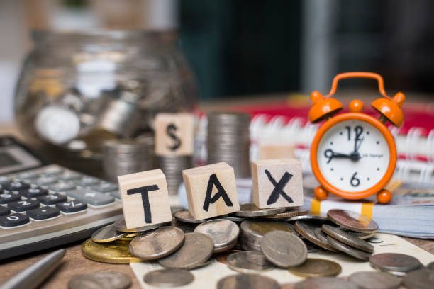 Taxes Word on Wood Block on Top of Coins Stack